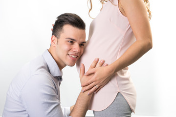 Happy and young pregnant couple in studio, white background