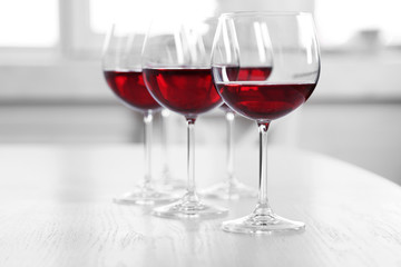 Glasses of red wine on table on bright background