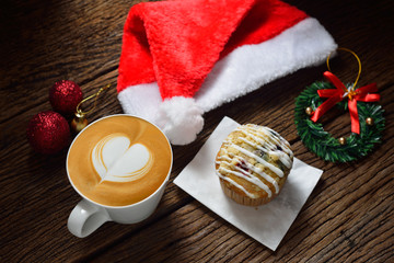 Latte Art, cup of cafe latte and cake surrounded by Christmas decorations on wooden background