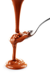Melted milky brown chocolate pouring from a spoon, isolated on white