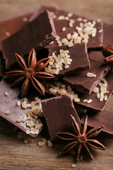 Black chocolate pieces with spices on wooden background