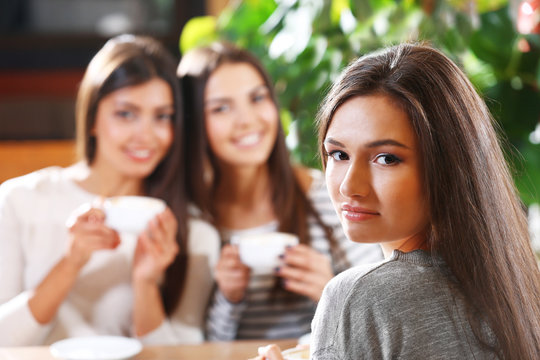 Beautiful girls drink coffee and speaking in cafe