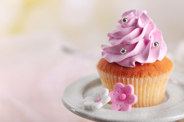 Tasty cupcake on stand, on light background