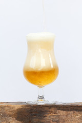 International beer day with pouring beer into glass on wood and white background.