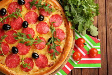 Tasty pizza with salami on decorated wooden table, close up