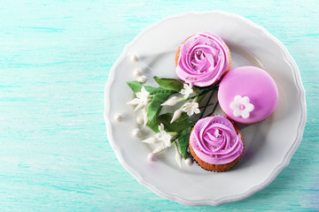 Tasty cupcakes on plate, on color wooden background