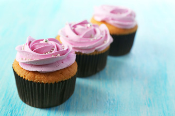 Tasty cupcakes on color wooden background