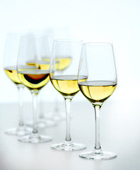 Wineglasses with white wine on wooden table on bright background