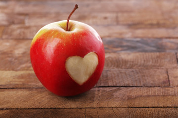 Apple with heart on wooden table