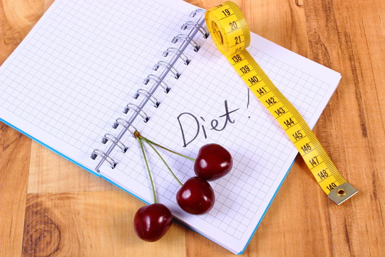Cherry and centimeter with notebook, slimming and healthy food