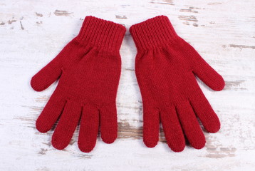 Pair of woolen gloves for woman on old wooden background