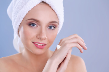 Young woman  putting cream on her hand Isolated on gray background