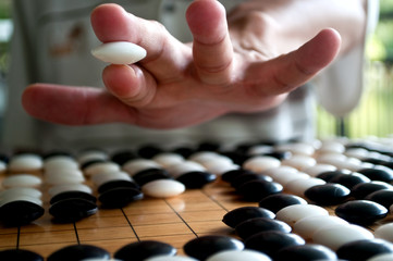 Go player hand holding white piece