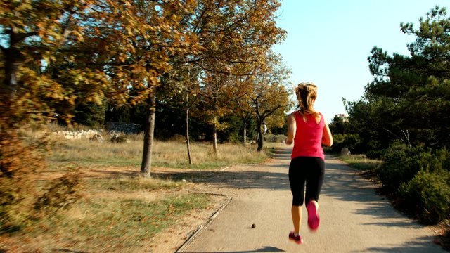 Young woman running in the park. Female runing away from the camera