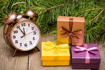 Clock over wooden background with fir tree and gift boxes