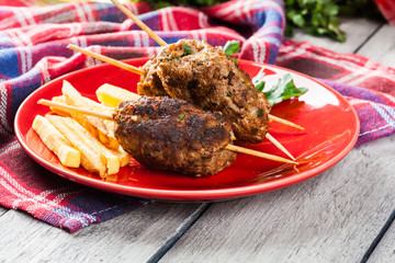 Barbecued kofta with fries on a plate