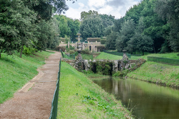 The paths among the trees and vegetation, a pond with river water and the historic fountains in the park at Vila Pamphili in Rome, capital of Italy