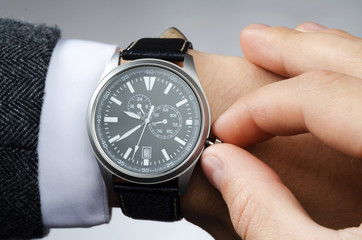 businessman adjusts the time on his wristwatch