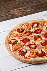 Delicious fresh pizza chicken ham tomato served on wooden table