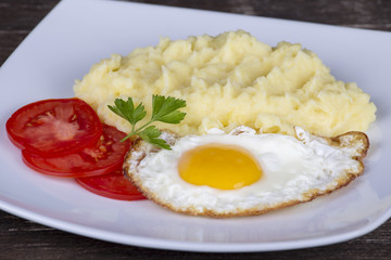 Mashed potatoes with fried eggs and tomato