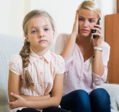 Worried mother calling doctor for daughter with abdominal pains