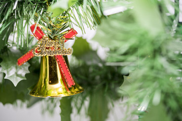 Christmas bell ornament hang on tree branch with green backgroun