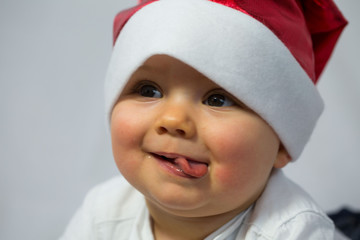 Baby mit Nikolausmütze streckt Zunge raush