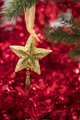 Christmas star ornament hang on tree branch with red bokeh backg