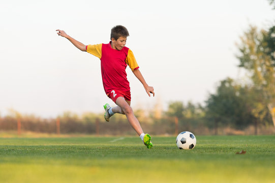 Fototapeta kid kicking a soccer ball