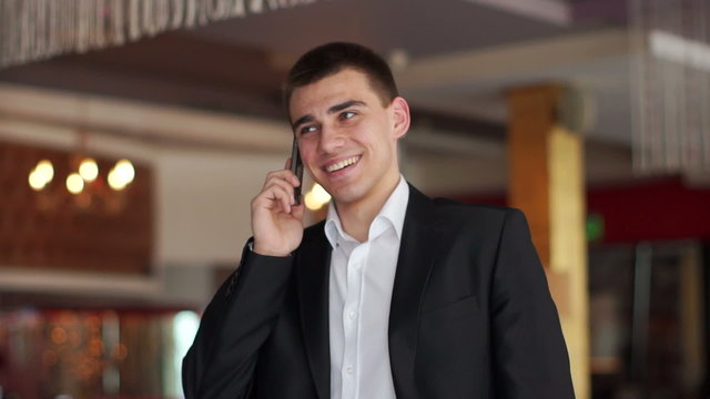 Young businessman talking on the phone and smiling at camera