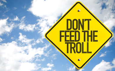 Don't Feed the Troll sign with sky background