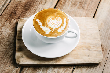 Cup of hot latte art coffee on wooden table
