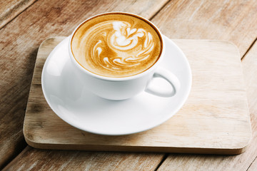Cup of hot latte art coffee on wooden table