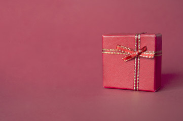 Red gift box isolated on red background. Left copyspace.