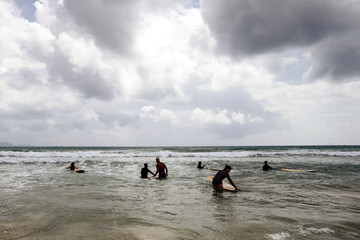 unidentified women surfers with surfing boards coming to the sea