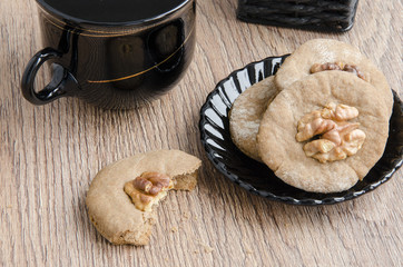 A cup of coffee and cookies with walnuts