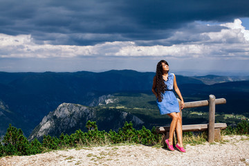 Naklejka na ściany i meble woman relax on peak of mountain with rainy sky