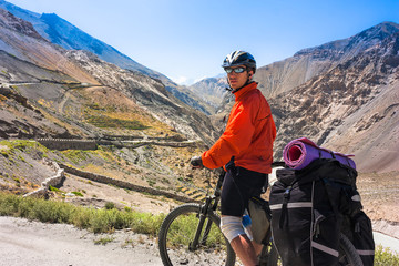 Fototapeta premium Young bicyclist standing on mountain road, Jammu and Kashmir State, North India