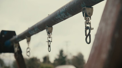 Abandoned broken empty derelict swings at urban playground chain hanging
