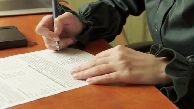 Woman signs a document.