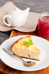 piece of cottage cheese pie with mint on a plate and jam