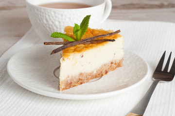 Vanilla cheesecake on a white plate and cup of tea