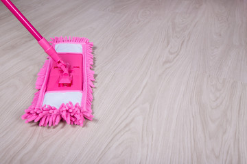 cleaning concept -close up of mop on wooden floor