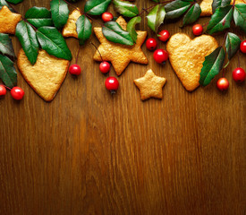 Christmas  wooden background decorated with holly, golden decorations and small red apples