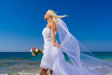 Fototapeta na wymiar Beautiful young bride walking on the beach