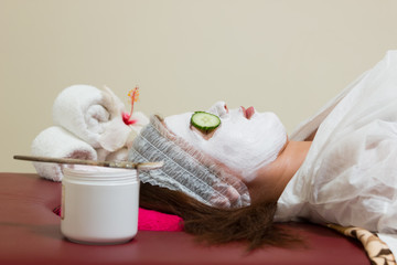 Woman with clay facial mask in beauty spa