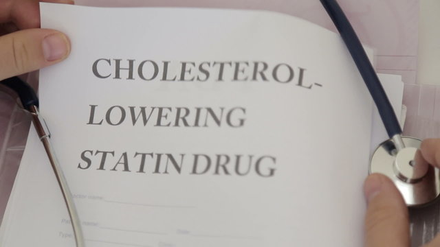 Doctor holding cholesterol lowering drugs papers