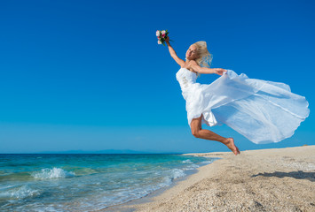 Beautiful young bride walking on the beach