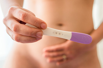 Pregnant woman holding positive pregnancy test