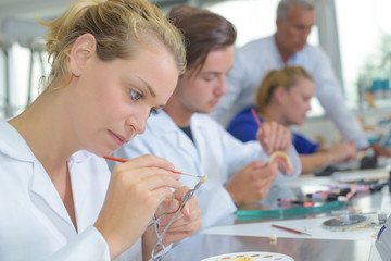 Female laboratory worker painting false tooth